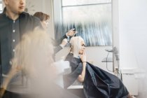 Парикмахер окрашивает волосы клиента, избирательный фокус — стоковое фото
