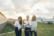 Three young women using confetti cannon outdoors — Stock Photo