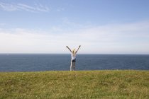 Ragazza con le braccia alzate in campo vicino al mare a Kaseberga, Svezia — Foto stock