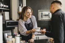 Barista serving cup of coffee to customer in cafe — Stock Photo