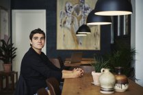 Молодой человек сидит в кафе, фокусируется на переднем плане — стоковое фото