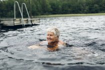 Mujer mayor nadando en Lake Kappemalgol, Suecia - foto de stock