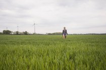 Trabajador agrícola caminando por el campo bajo cielo nublado - foto de stock