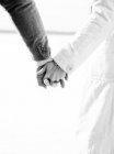 Cropped view of man and woman holding hands, black and white — Stock Photo
