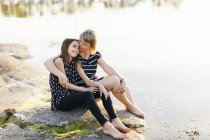 Мати і дочка сидять на морі на заході, фокус на передньому плані — стокове фото