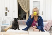 Mujer con perro en el sofá beber de la taza amarilla, se centran en primer plano - foto de stock