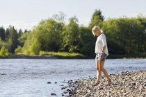 Вид збоку жінки на березі річки, фокус на передньому плані — стокове фото