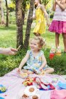 Mãe que dá doces de filha no piquenique de aniversário — Fotografia de Stock