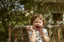 Crying girl sitting in backyard, focus on foreground — Stock Photo