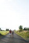 Padre e hija caminando por el camino rural en Smaland, Suecia - foto de stock