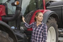 Agricultural worker standing next to tractor at field — Stock Photo