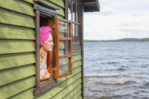 Mujer adulta mirando por la ventana de la sauna - foto de stock