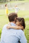 Батько і дочка обіймаються в парку, зосередьтеся на передньому плані — стокове фото