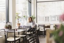 Woman talking on smart phone by laptop in cafe, selective focus — Stock Photo