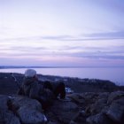 Femme assise sur des pierres et regardant en mer — Photo de stock
