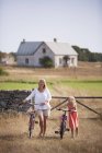 Mother and daughter wheeling bicycles at farm — Stock Photo