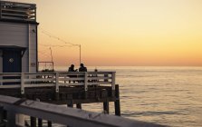 Malerischer Blick auf die Seebrücke bei Sonnenuntergang und die Silhouetten der Menschen — Stockfoto