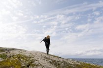 Windige Frau in Schwarz steht auf Felsen — Stockfoto