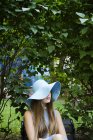 Portrait of teenage girl in hat against plants — Stock Photo