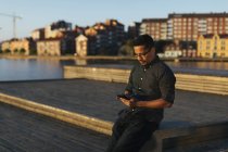 Чоловік сидить на прогулянці і використовує смартфон — стокове фото