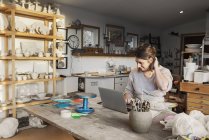 Woman using laptop in pottery workshop — Stock Photo