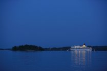 Passenger ferry illuminated at night, reflecting in water — Stock Photo