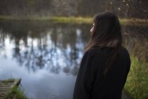 Женщина, стоящая на берегу реки и наблюдающая за видом — стоковое фото