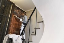 Pintor pintando puerta en edificio de apartamentos - foto de stock