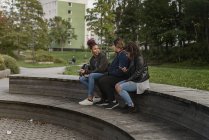 Amis assis ensemble dans le parc, objectif sélectif — Photo de stock