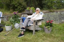 Seniorin sitzt auf Liegestuhl im Garten — Stockfoto