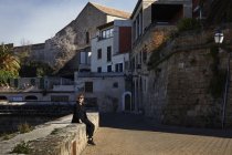 Femme assise sur un mur de pierre par des bâtiments à Majorque, Espagne — Photo de stock