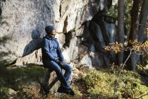 Man wearing beanie and jacket sitting by cliff — Stock Photo