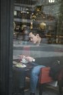 Hombre joven sentado en la cafetería, enfoque selectivo - foto de stock