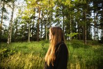 Jeune femme en forêt au coucher du soleil — Photo de stock