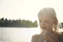 Девушка сзади освещена солнечным лучом перед озером — стоковое фото