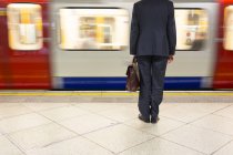 Homme d'affaires attendant un train de métro à la gare de Londres, Royaume-Uni, Angleterre — Photo de stock