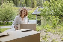 Жінка переносить картонну коробку в будинок — стокове фото