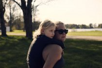 Femme adulte d'âge moyen donnant du piggyback à une fille dans un parc — Photo de stock
