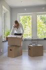 Женщина распаковывает картонные коробки в новом доме — стоковое фото