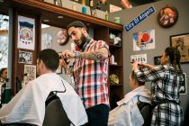 Barberes corte o cabelo do cliente na barbearia — Fotografia de Stock