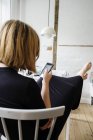 Молодая женщина сидит и смотрит на мобильный телефон — стоковое фото