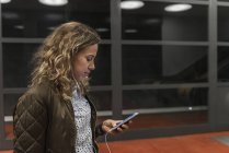 Mulher jovem olhando para o telefone celular na estação de metrô — Fotografia de Stock