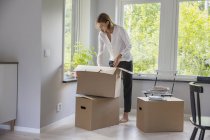 Жінка розпаковує картонні коробки в новому будинку — стокове фото