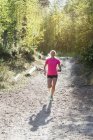Donna che corre nella foresta, attenzione selettiva — Foto stock