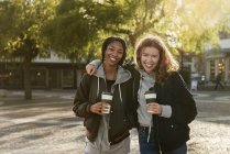 Smiling teenage girls with coffee cups — Stock Photo