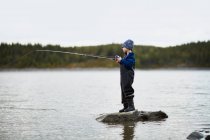 Adorable little boy fishing in river — Stock Photo