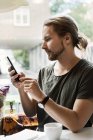 Young man with smart phone in cafe, selective focus — Stock Photo