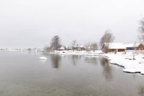 Дома в снегу на озере, избирательный фокус — стоковое фото