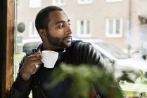 Young man with cup of coffee in cafe, selective focus — Stock Photo