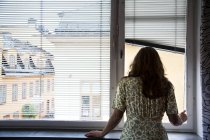 Woman looking through window, back view — Stock Photo